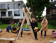 Sandkasten mit Nestschaukel, in dem Kinder mit Sandspielzeug spielen und nita Vondermaßen, Fachbereich KiTa und Kindertagespflege, Michaela Sprenger, STAWAG und Nadia von Thenen, stellvertretende KiTa-Leiterin dabei stehen