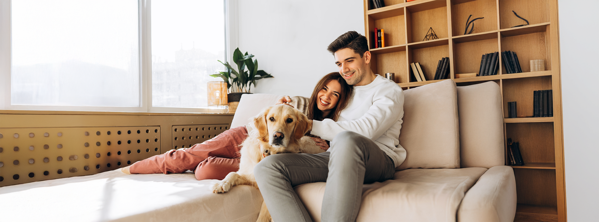 Mann sitzt auf Sofa im Wohnzimmer und Frau liegt in seinem Arm