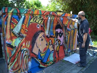 bärtiger Mann vollendet buntes Graffiti auf Stawag Trafostation in Aachen
