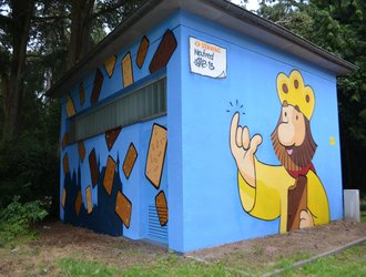 Streetart König mit angebissenem Keks in der Hand auf blauer Stawag Trafostation in Aachen