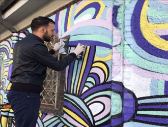 Mann auf Leiter sprüht Graffiti auf STAWAG Trafostation in Aachen