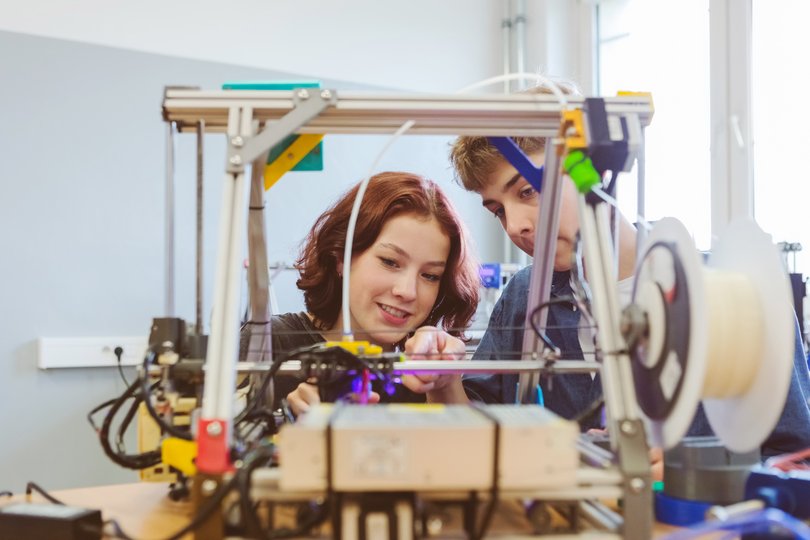 Eine Schülerin und ein Schüler bauen an einem Modell.