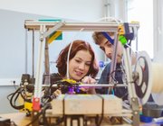 Eine Schülerin und ein Schüler bauen an einem Modell.