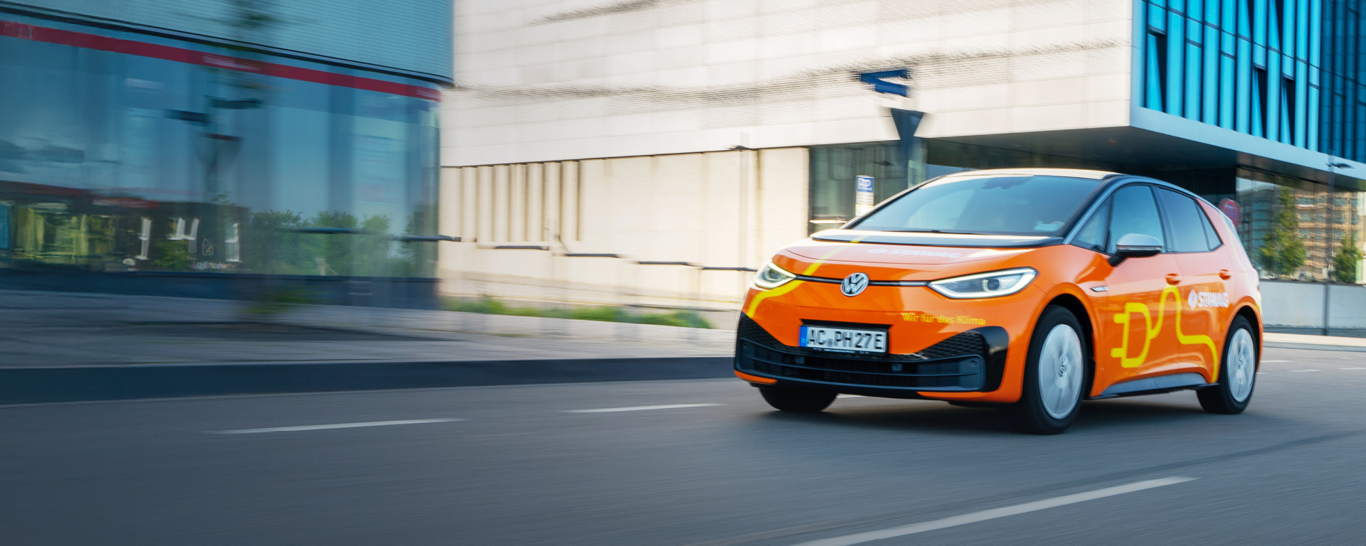 VW id3 im STAWAG-Design fährt auf Straße vor Gebäude vorbei