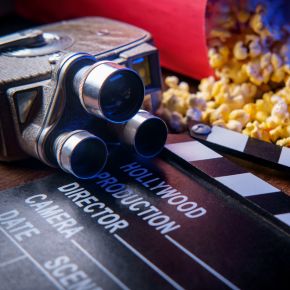 Filmklappe, Filmprojektor und Popcorn liegen darauf