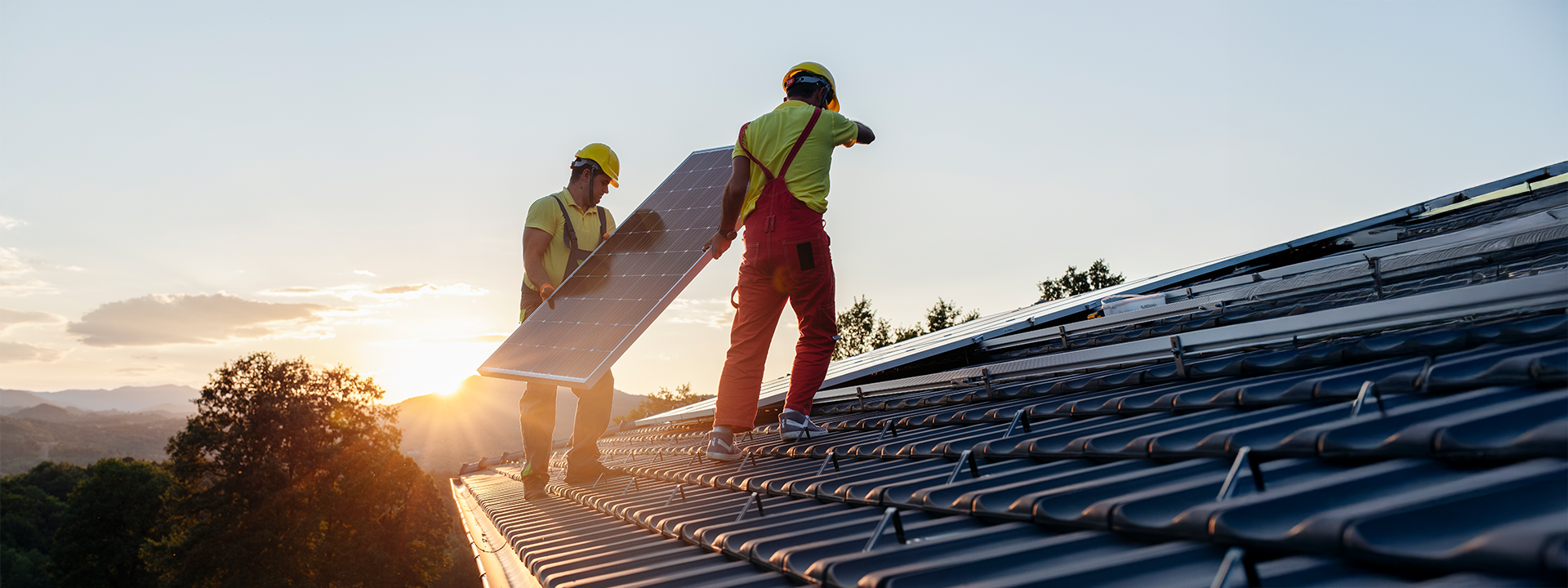 Zwei Monteure halten Solarmodul auf Dach