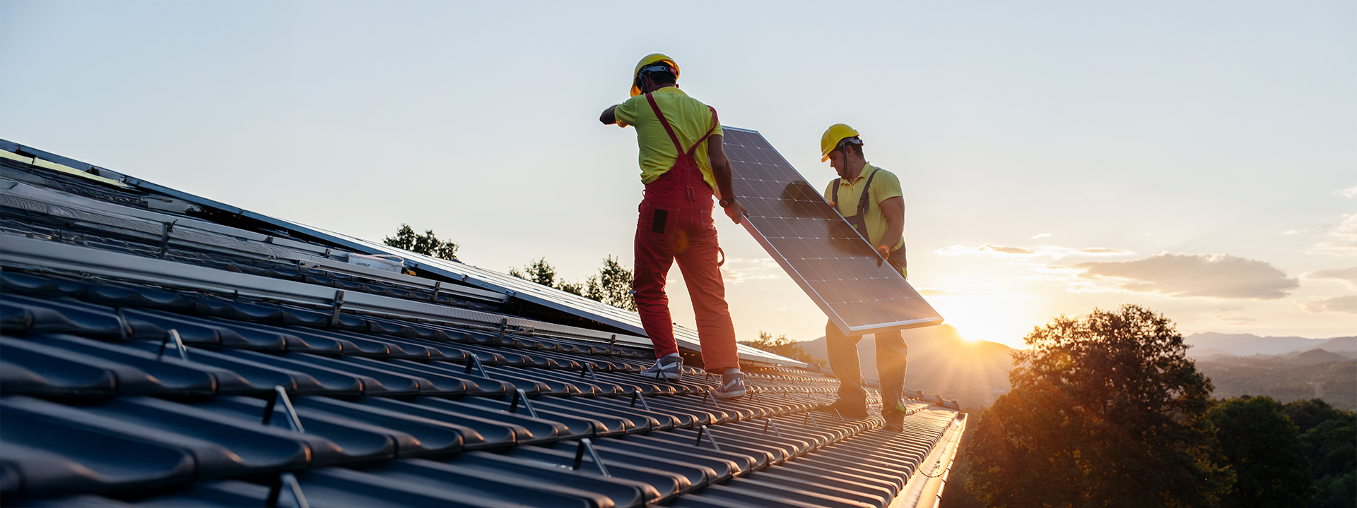 Zwei Monteure halten Solarmodul auf Dach