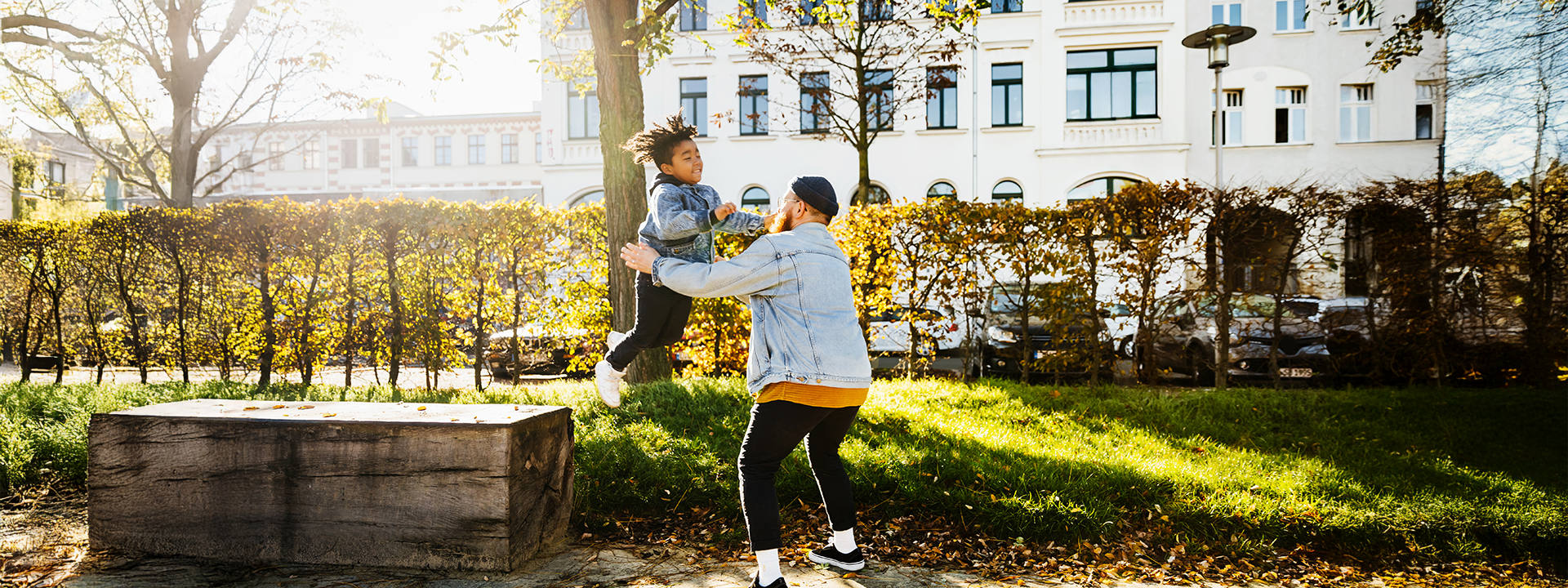 Mann fängt in Park Kind auf, das von Parkbank springt